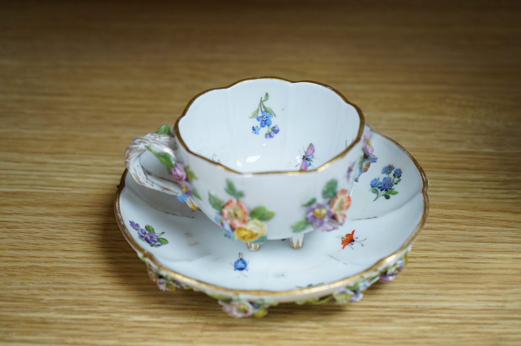 A 19th century Meissen floral encrusted cup and saucer, 14cm diameter